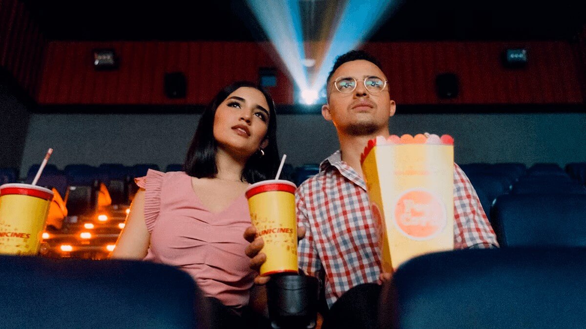 A male and female couple watch a movie in a theatre