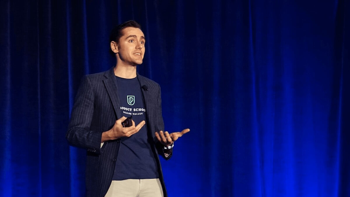 a male presenter speaks to an audience at a conference